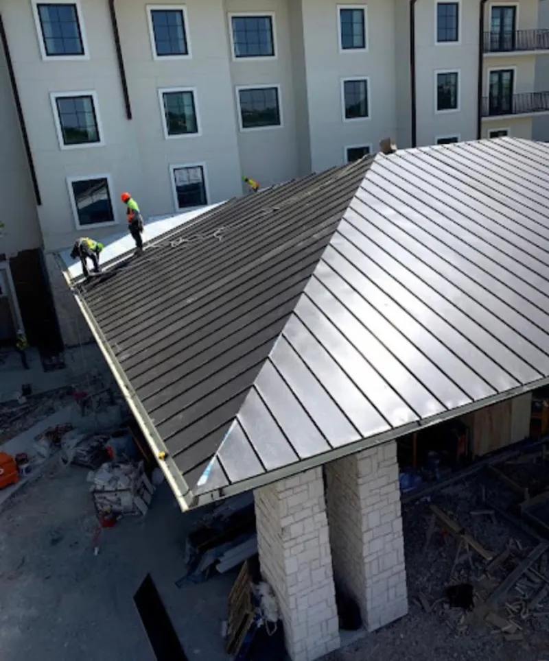 Crew installing standing seam metal roof panels on a commercial project in Winfield